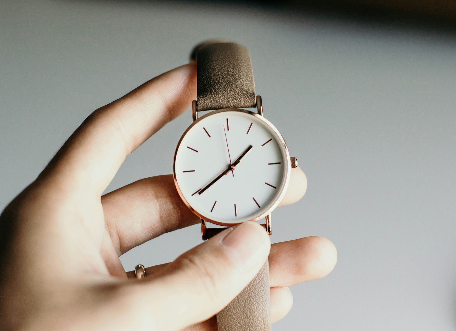 Classic analog wristwatch with white dial and brown leather strap on a plain background